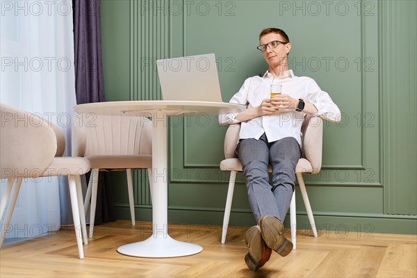 Relaxed middle aged man with laptop at home