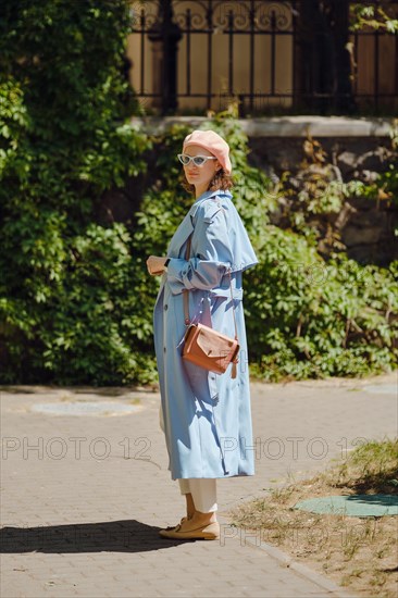 Woman in blue cloak and coral beret stopped and turned back