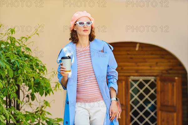 Modern business woman leaving cafe with glass of coffee