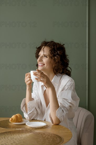 Young woman with toothy smile holding cup in her hands