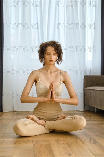 Meditative woman sits in lotus position at home