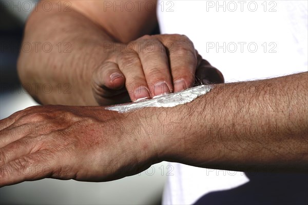 Man puts on sunscreen