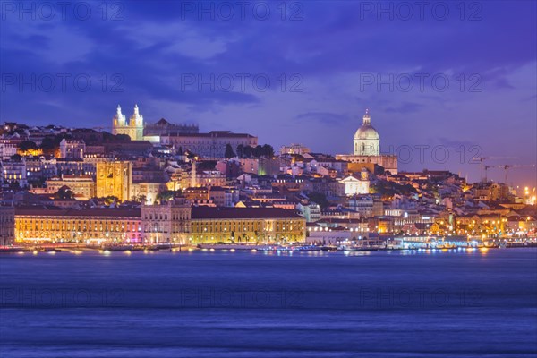 View of Lisbon over Tagus river with passing ferry boat from Almada with ferry in evening twilight