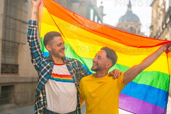 Portrait of gay male couple with rainbow flag at pride party in the city