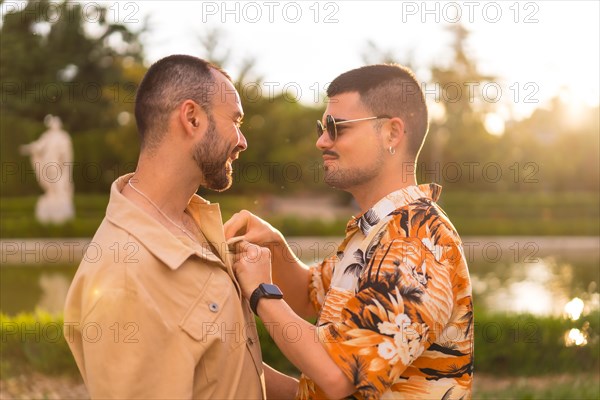 Homosexual couple embracing giving each other a kiss looking at the sunset in a park in the city