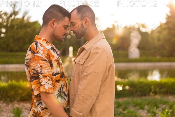 Romantic portrait of homosexual couple embracing at sunset in a park in the city