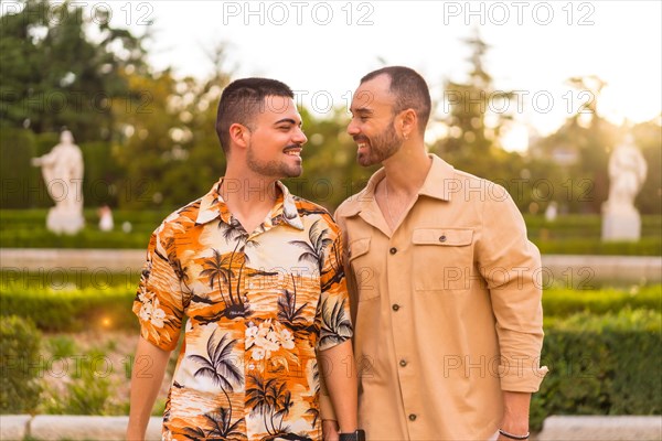 Romantic portrait of gay newlyweds walking in the sunset in a park in the city