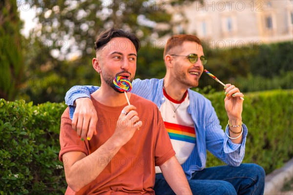 Portrait of smiling wedding couple eating a lollipop in the park on sunset in the city