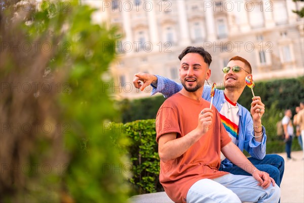 Smiling wedding couple eating a lollipop in the park on sunset in the city