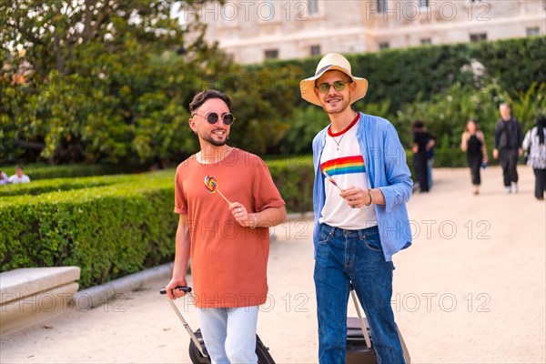 Male tourists gay boyfriends with a suitcase in the park on sunset in the city visiting the city