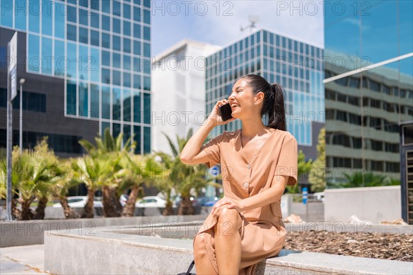 Portrait of a Latin woman executive or businesswoman in a business office area talking on the phone sitting