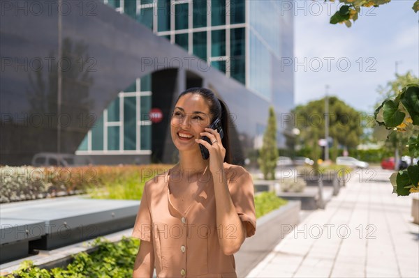 Latin woman executive or businesswoman in a business office area leaving work talking on the phone