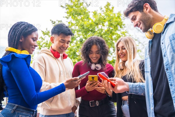 Low angle view of a group of young multi-ethnic teenage friends using cell phones on campus in the city