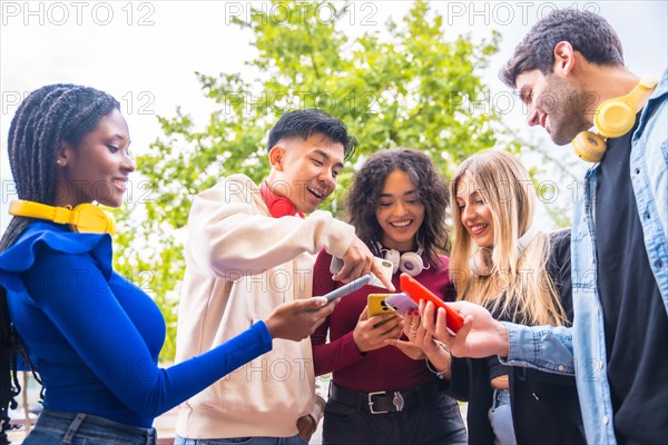 A group of young multi-ethnic teenage friends using cell phones in the city campus