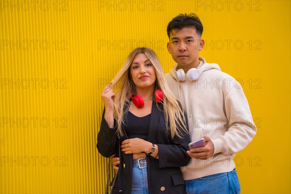 Portrait of multi-ethnic couple of Asian man and Caucasian woman on a yellow background