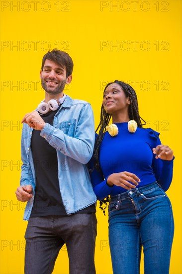 Multiethnic wedding couple of Caucasian man and woman of black ethnicity on a yellow background having fun