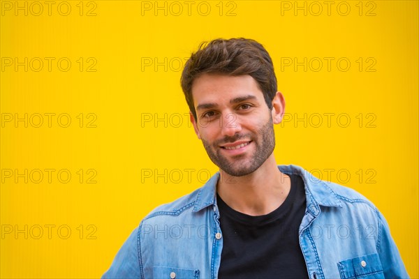 Portrait of a handsome excited model man in basic clothes smiling isolated over yellow background