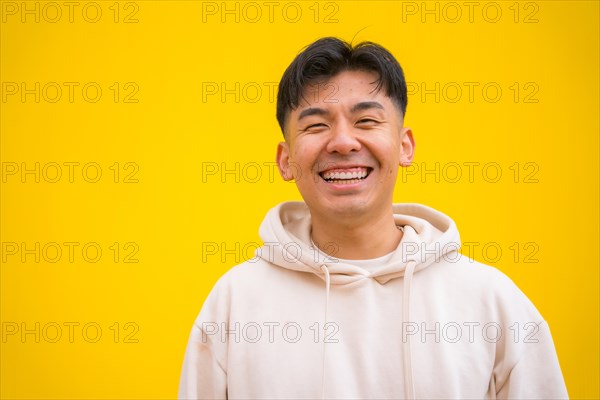 Portrait of a handsome Asian man in basic clothes smiling isolated over yellow background