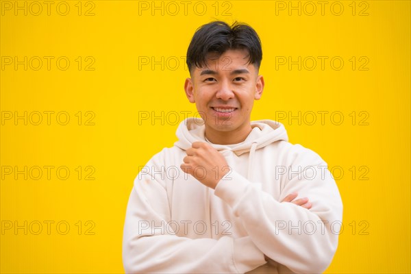 Portrait of a handsome South Korean Asian man in basic clothes smiling isolated over yellow background