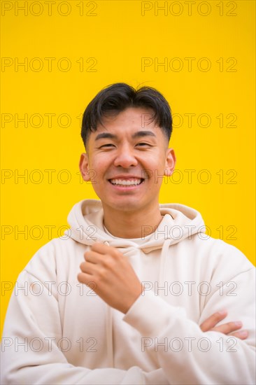 Portrait of a handsome South Korean Asian man in basic clothes smiling isolated over yellow background