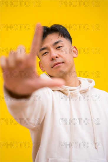 Portrait of a south korean man in basic clothes over yellow background