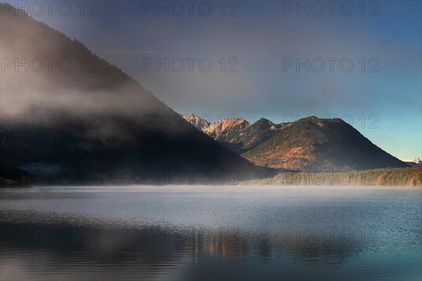 Fog gives way to sun at autumn sunrise at Sylvensteinsee