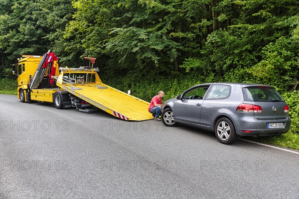 Defective VW Golf behind tow truck at roadside