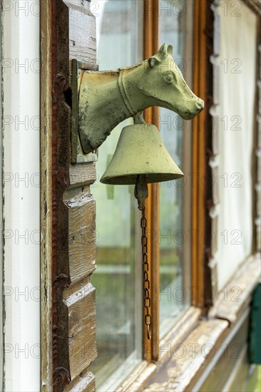 A cows head with a bell on a door