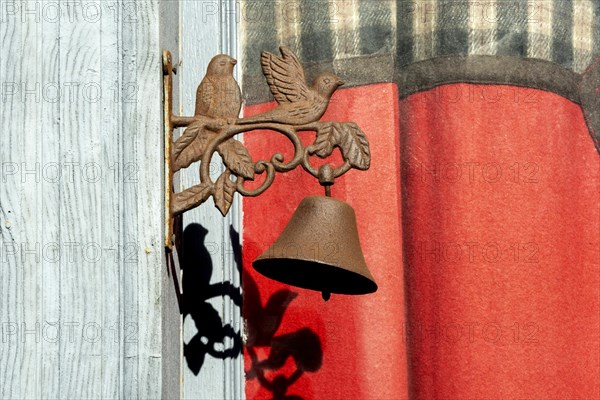 Two birds with a bell on a door