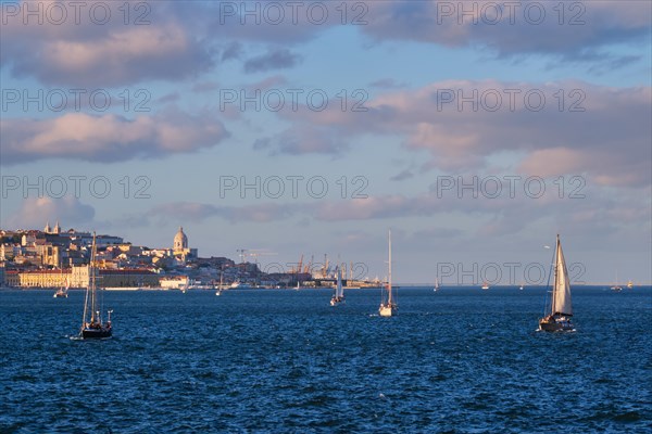 View of Lisbon over Tagus river from Almada with yachts tourist boats at sunset with dramatic sky