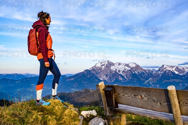 Mountaineer next to a wooden bench enjoying the view towards Hoher Göll