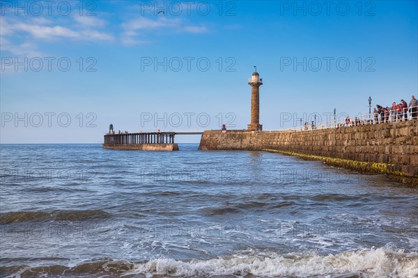 View of beach and pier with 19th century stone lighthouse