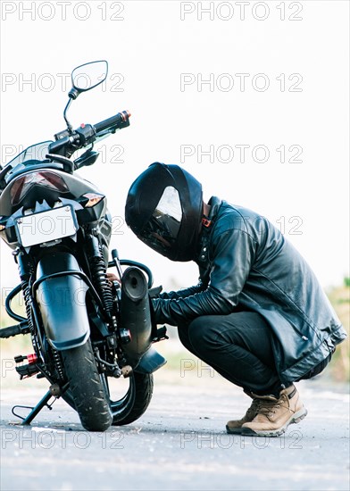 Man checking his motorcycle on the road