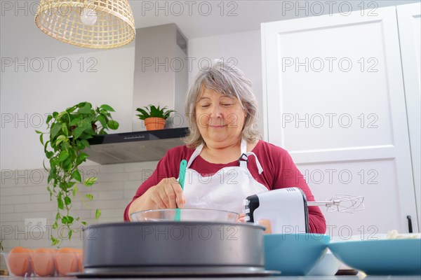 Female cook in white apron beating eggs in a bowl with a spatula