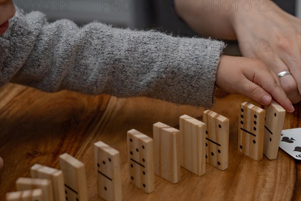 Child's hands in gray sweater playing dominoes with blurred focus