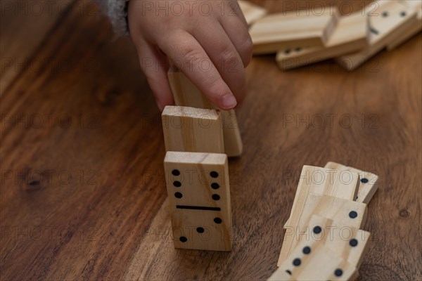 Child's hands in gray sweater playing dominoes with blurred focus