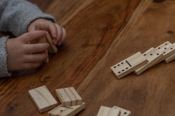 Child's hands in gray sweater playing dominoes with blurred focus