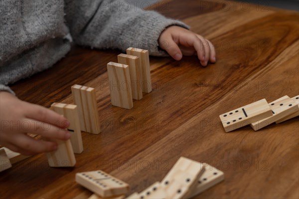 Child's hands in gray sweater playing dominoes with blurred focus