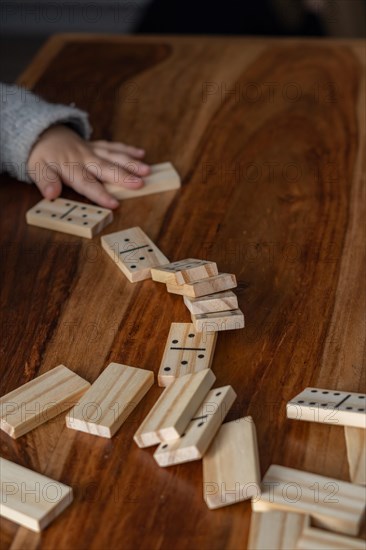 Child's hands in gray sweater playing dominoes with blurred focus