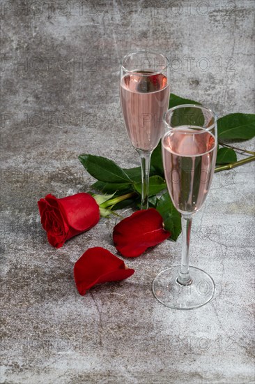 Two glasses of champagne and a rose on a white background and copy space valentine's day symbol