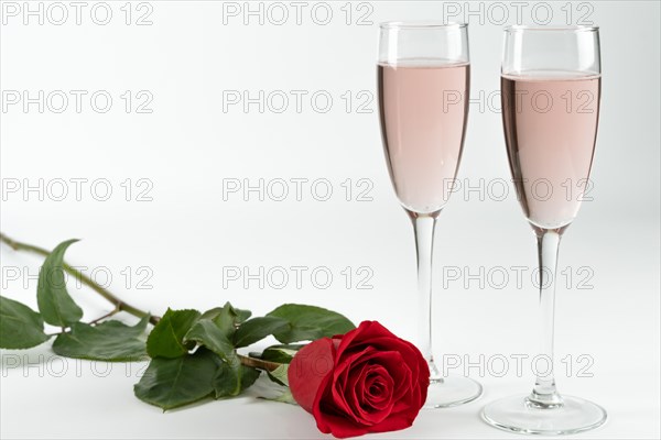 Two glasses of champagne and a rose on a white background and copy space valentine's day symbol