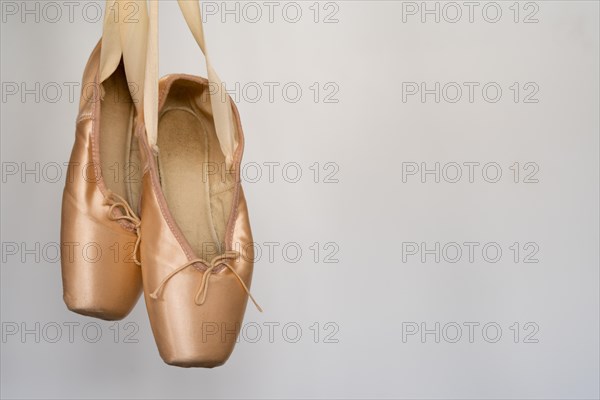 Ballet slippers with orange ribbon on a wooden floor and white background