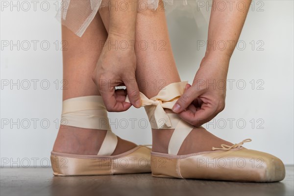 Legs of girl dancing ballet with tulle skirt and pink shoes different dance steps wooden floor and white background with copy space