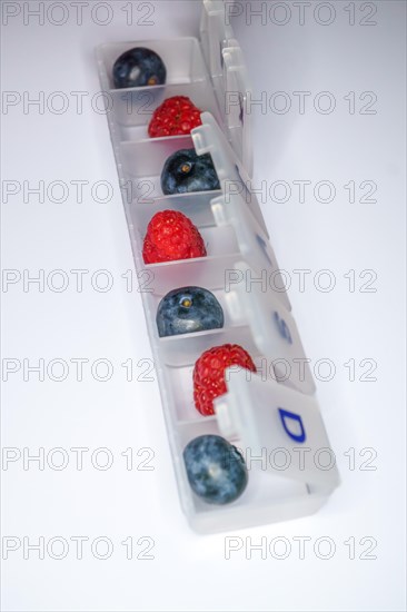 Blueberries and raspberries in a pill box drug-free health concept