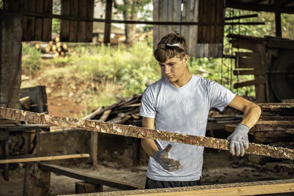 Young man working in a sawmill wearing protective gloves