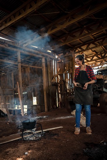 The young woman in uniform working in a factory cooking for the all with fire on the floor