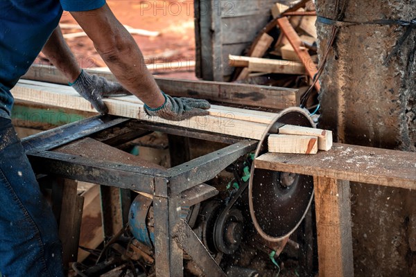 Close-up detail shot of a circular saw in operation with worker's hands and dust in the air