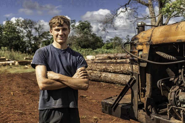 Young worker standing with arms crossed smiling and looking at the camera in a sawmill