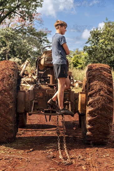 Young man standing on tractor at sawmill