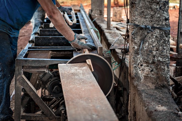 Detail of man's hands with a piece of wood in a cutting machine